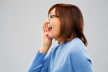 Image showing senior woman in glasses calling over grey