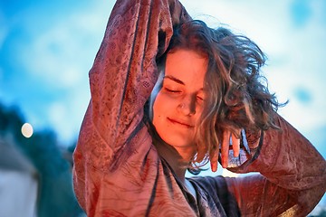 Image showing Young woman dancing in the light of fire at dusk