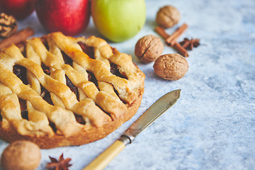 Image showing Tasty sweet homemade apple pie cake with cinnamon sticks, walnuts and apples