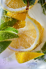 Image showing Slices of lemon and lime with bubbles of water in a glass. Macro photo of refreshing lemonade