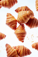 Image showing Falling fresh french croissants with crumbs on a light background.