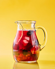 Image showing Fruit berry homemade lemonade in a glass jug on a yellow background with copy space. Healthy drink