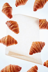 Image showing Floating freshly baked croissant on a light background of parchment paper, mock up.