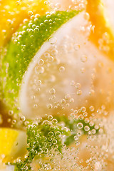 Image showing Homemade refreshing drink made from lemon and lime slices with bubbles. Macro photo of summer healthy lemonade