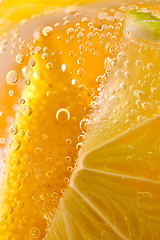 Image showing Macro photo of yellow lemon slices with lots of bubbles in a glass with water. Summer cold lemonade