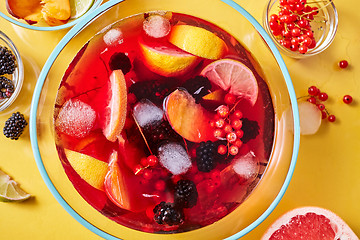 Image showing Top view on glass jug with homemade fruit berry drink with ice cubes on yellow background