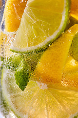 Image showing Macro photo of sliced lemon and lime with a leaf of mint and bubbles in glass. Cool drink mojito