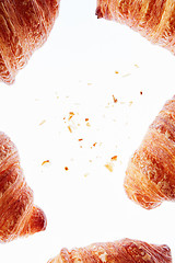 Image showing Frame of fresh homemade croissants with crumbs on a light background.