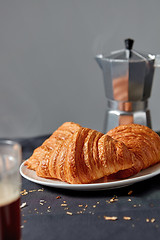 Image showing Coffee maker with homemade croissant on a gray background.