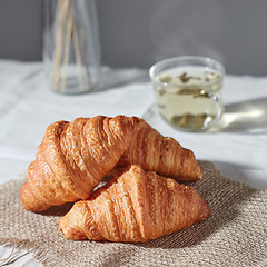 Image showing Close up homemade fresh croissants and green tea on a gray background.