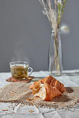 Image showing Breakfast still life with green tea and fresh croissanta on a grey background.