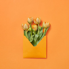 Image showing Post card with bouquet of tulips in craft envelope on an orange background.