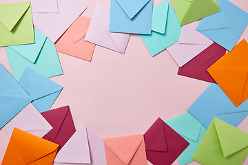 Image showing Decorative frame from colorful craft envelopes on a light pink background.