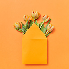 Image showing Mock up envelope with yellow tulips on an orange background.