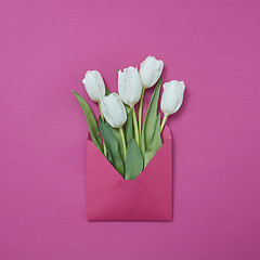 Image showing White tulips in an envelope on a purple background.