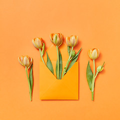 Image showing Fresh tulips in a handmade envelope on a yellow background.