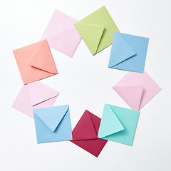 Image showing Round frame of colored craft blank envelopes on a light background.