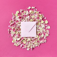 Image showing Mockup handmade envelope on a round frame from petals on a magenta background.