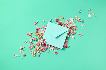 Image showing Greeting post card with flowers petals and envelope on a light turquoise background.