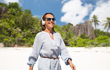 Image showing woman with headphones walking along summer beach