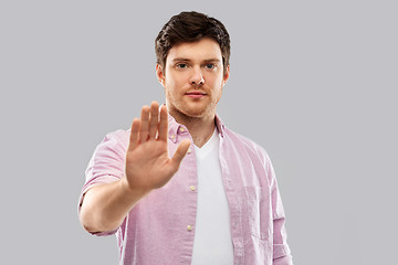 Image showing serious young man showing stop gesture