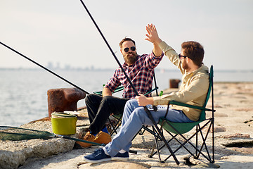 Image showing happy friends with fishing rods on pier