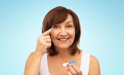 Image showing happy senior woman applying contact lenses