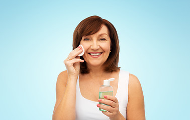 Image showing senior woman cleaning face by lotion on cotton pad