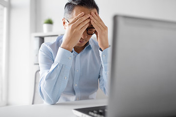 Image showing stressed businessman with laptop working at office