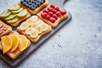 Image showing Wholegrain bread slices with peanut butter and various fruits