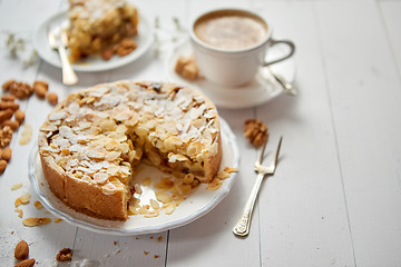 Image showing Whole delicious apple cake with almonds served on wooden table