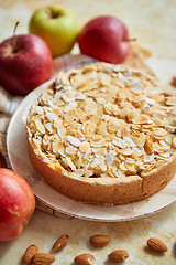 Image showing Freshly baked homemade apple pie with almond flakes cake on yellow