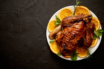 Image showing Roasted whole chicken or turkey served in white ceramic plate with oranges