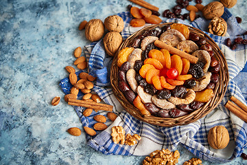 Image showing Composition of dried fruits and nuts in small wicker bowl placed on stone table