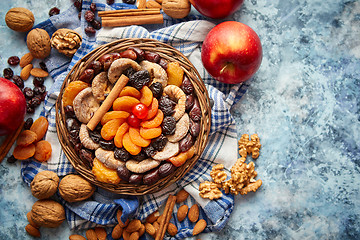 Image showing Composition of dried fruits and nuts in small wicker bowl placed on stone table