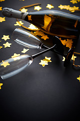 Image showing Glasses and bottle of champagne with golden serpentines and confetti