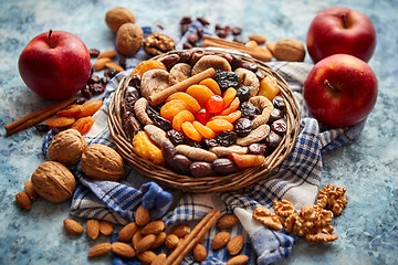 Image showing Composition of dried fruits and nuts in small wicker bowl placed on stone table