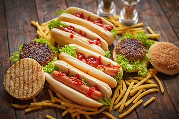 Image showing Fastfood assortment. Hamburgers and hot dogs placed on rusty wood table