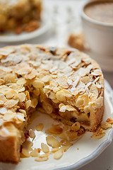 Image showing Whole delicious apple cake with almonds served on wooden table