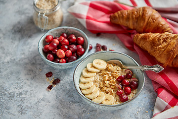 Image showing Ceramic bowl of oatmeal porridge with banana, fresh cranberries and walnuts