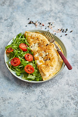 Image showing Classic egg omelette served with cherry tomato and arugula salad on side