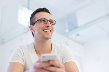 Image showing young man using a mobile phone  at home