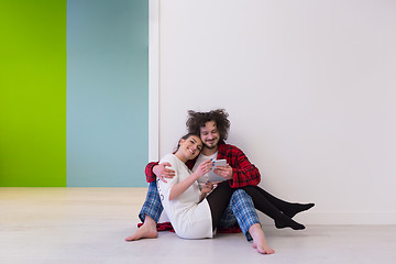 Image showing Young Couple using digital tablet on the floor