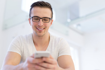 Image showing young man using a mobile phone  at home