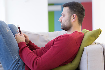 Image showing young man using a mobile phone  at home