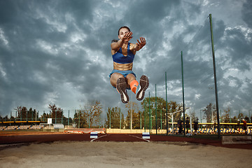 Image showing Female athlete performing a long jump during a competition