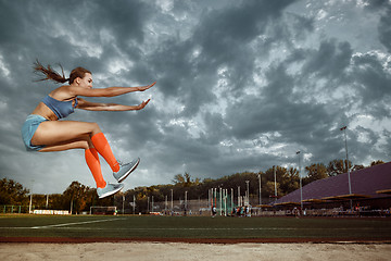 Image showing Female athlete performing a long jump during a competition