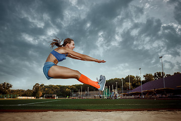 Image showing Female athlete performing a long jump during a competition