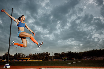 Image showing Female athlete performing a long jump during a competition