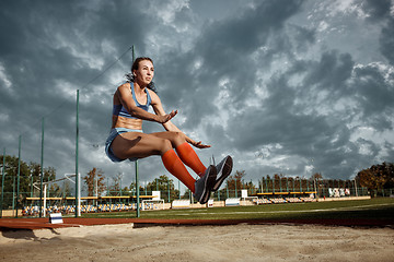 Image showing Female athlete performing a long jump during a competition